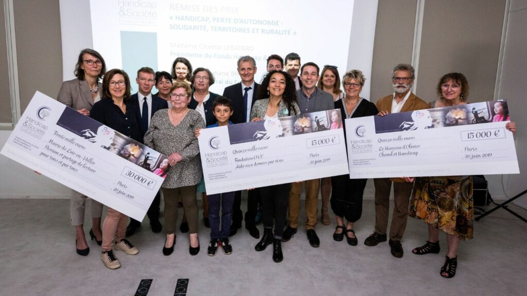 Photo d'un groupe de personnes tenant entre leurs mains de grands chèques à l'ordre du Fonds Handicap & Société