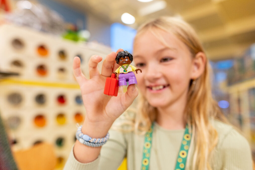 Un enfant qui tient un personnage LEGO dans une magasin